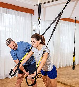Trainer zeigt einem Gast eine Fitnessübung